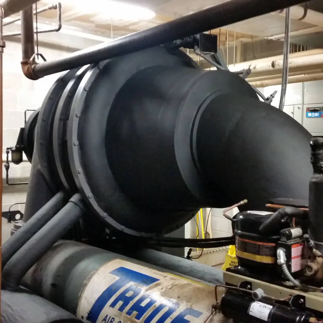 A large black pipe sitting next to a machine.