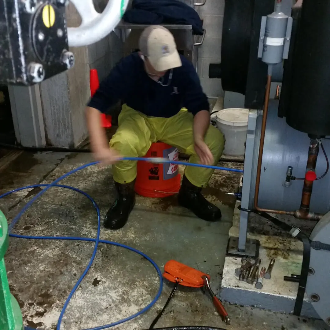 A man working with a hose in a room wearing a yellow safety pant