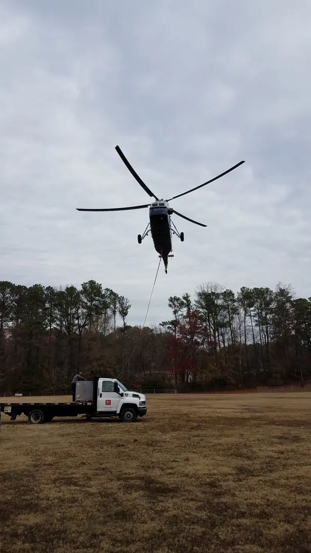 A chopper lifting off with a rope coming down and a truck in the ground