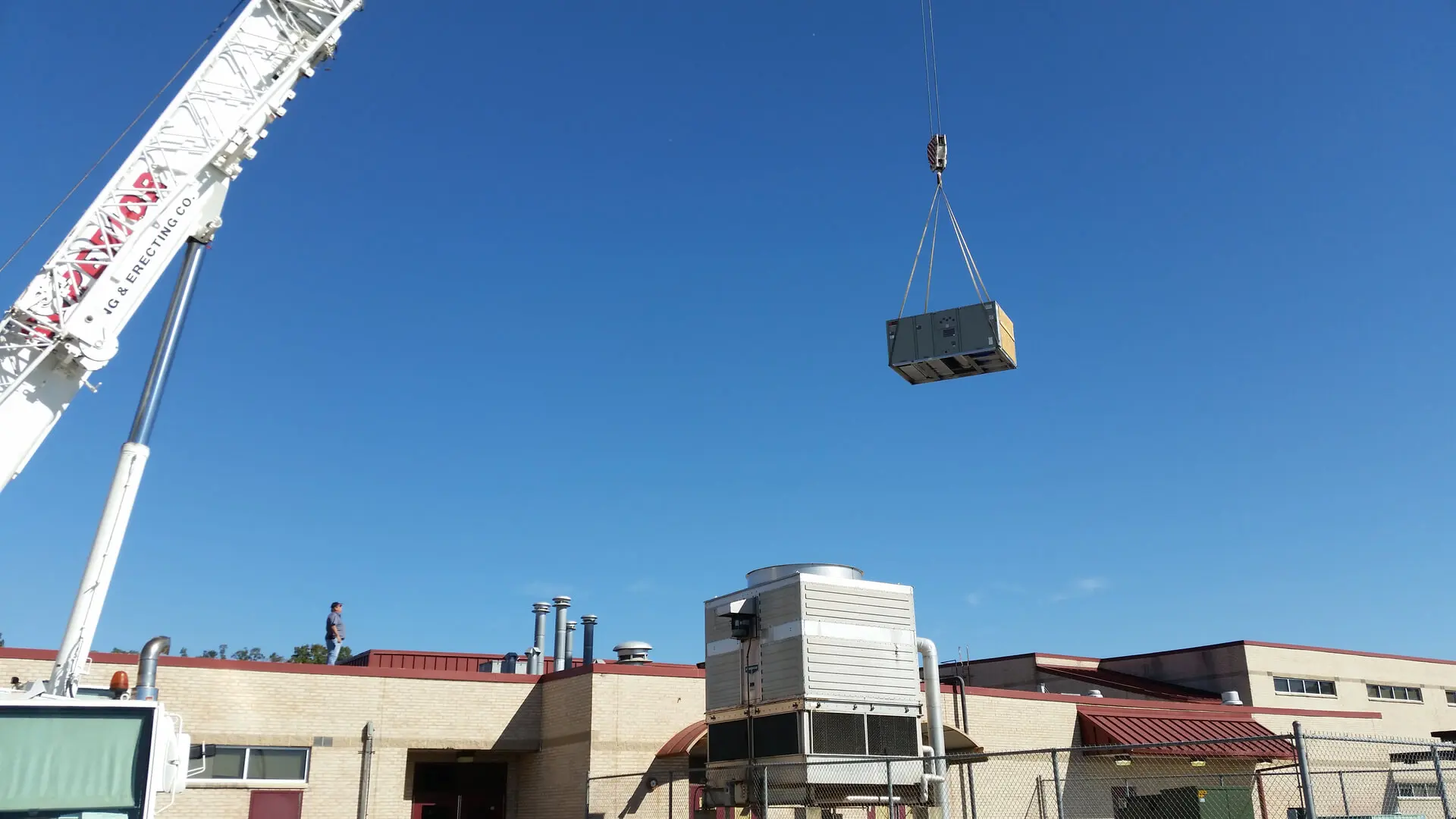 A crane is lifting a large box onto the roof of a building.