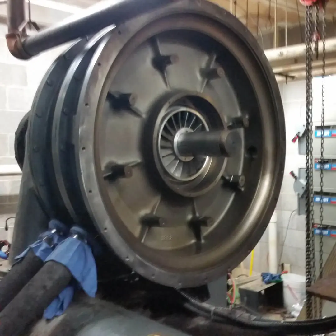A large metal wheel in a machine shop. with chains all around
